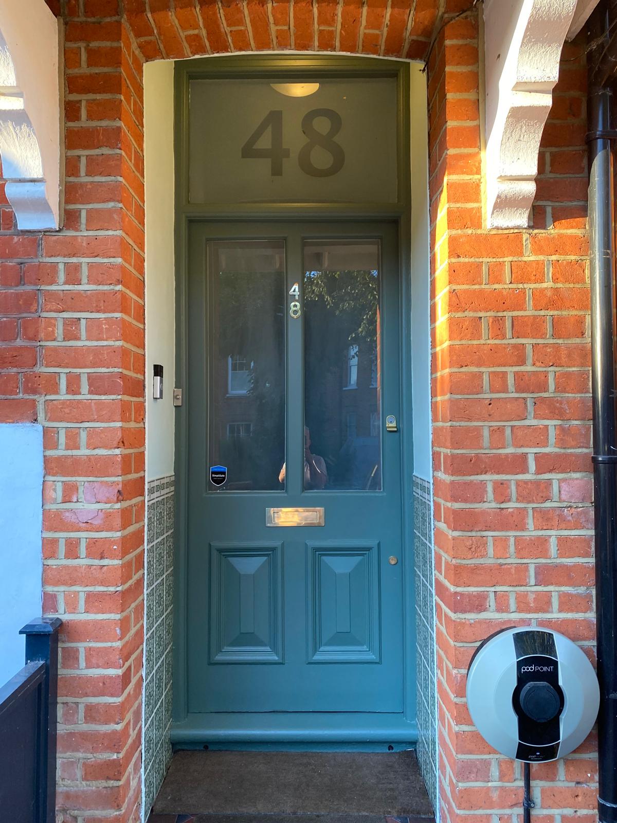 Newly painted Victorian front door in deep heritage green with masking recently removed in Epsom
