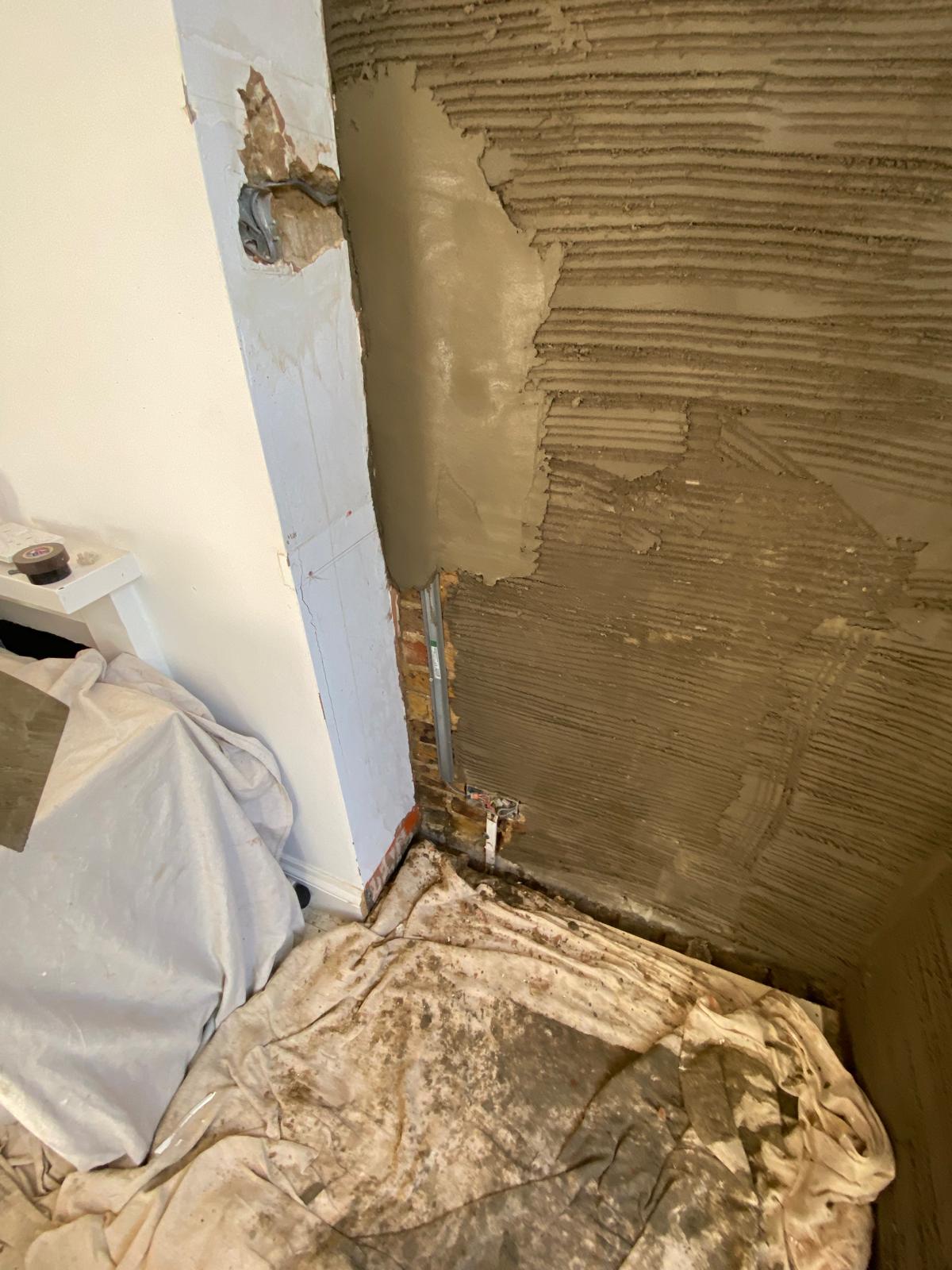 Sand and cement scratch coat being applied to internal wall in Epsom with corner beading in place