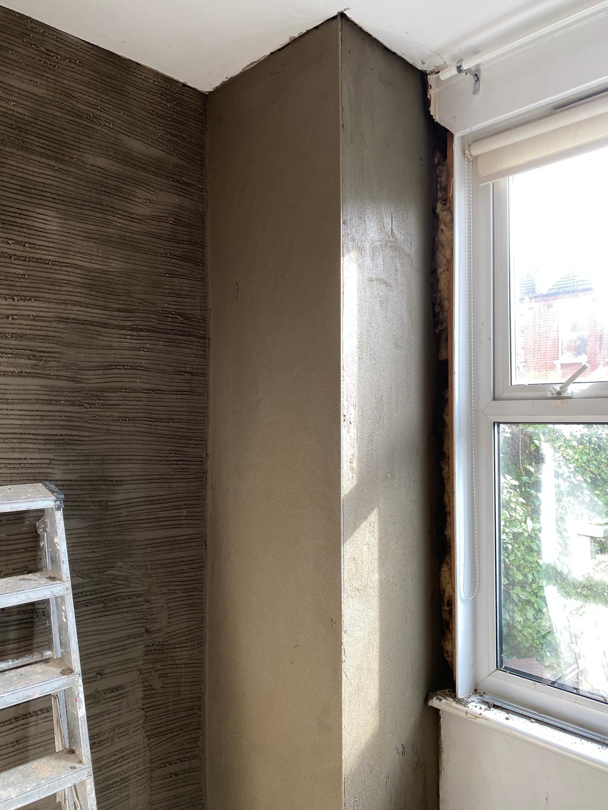 Side by side contrast of keyed scratch coat and smooth plastered window reveal during replastering job in Epsom