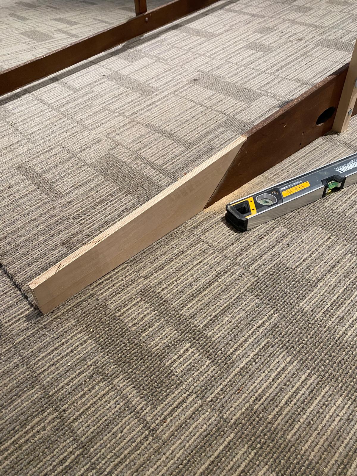 Spirit level and tapered timber packer used during handrail installation — joinery repair work by Epsom handyman Jonathan Mills