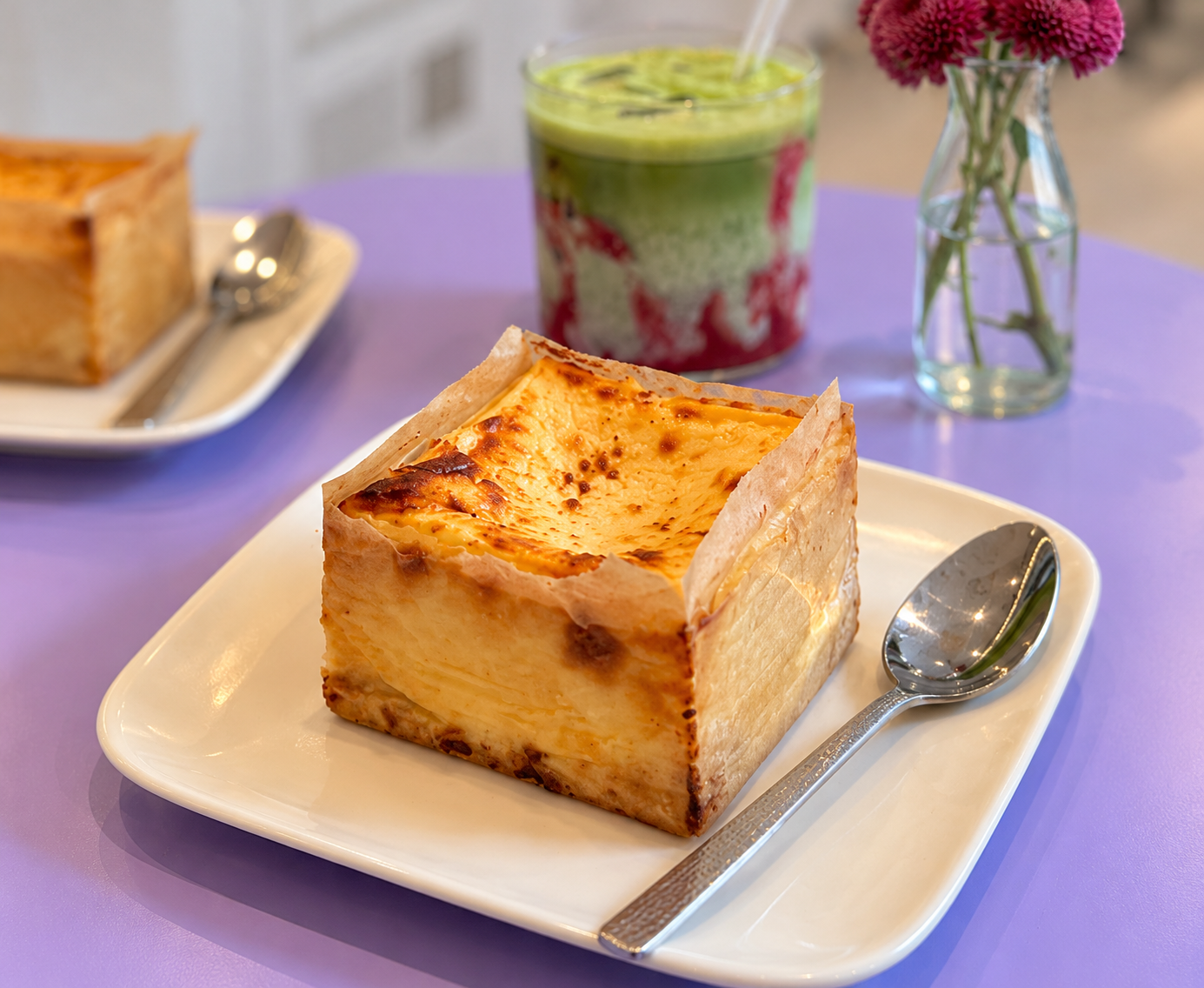 Basky Basque cheesecake Cube with a caramelised top, served on the lilac boutique table with an iced matcha