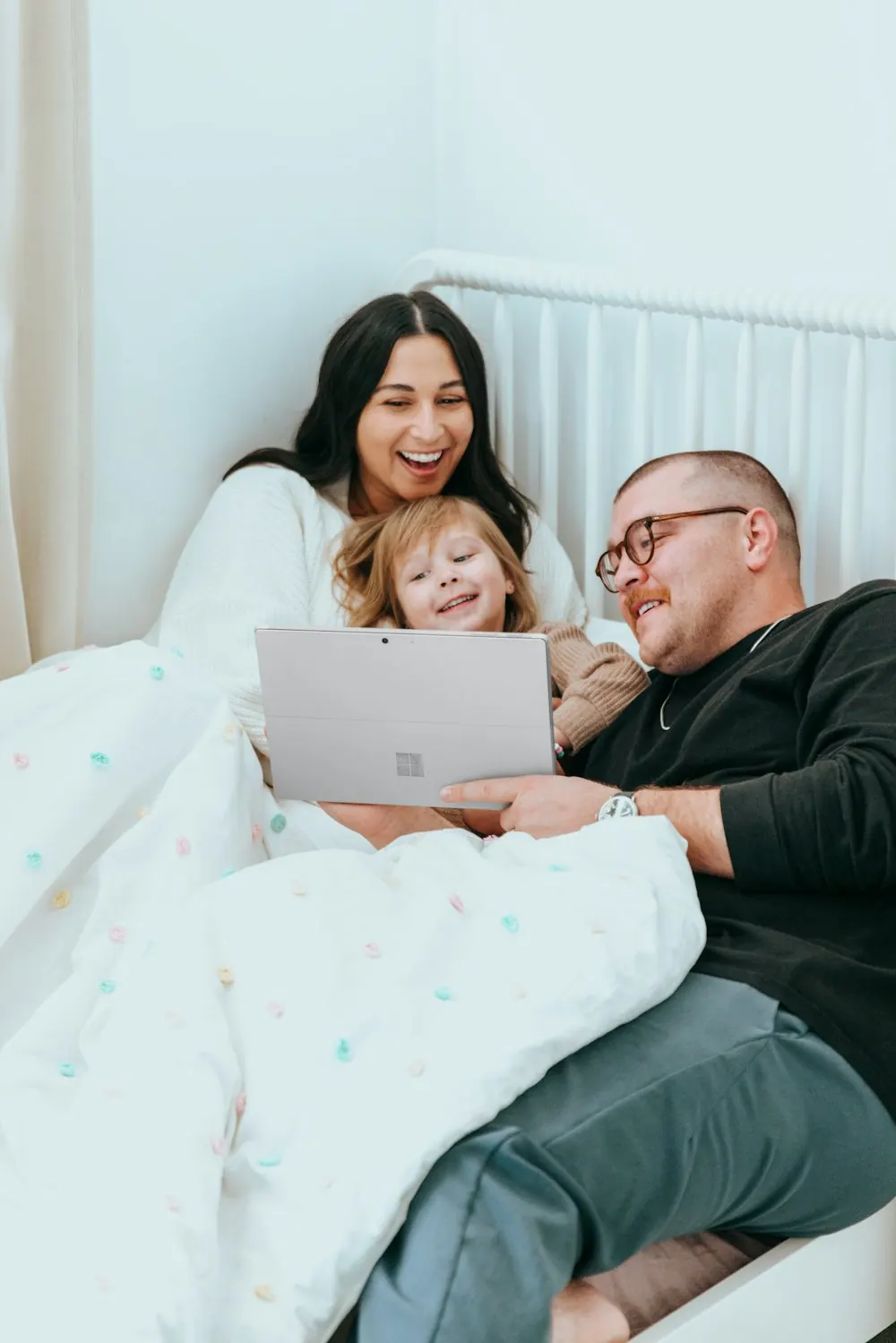 Parents and their daughter smiling at a laptop together