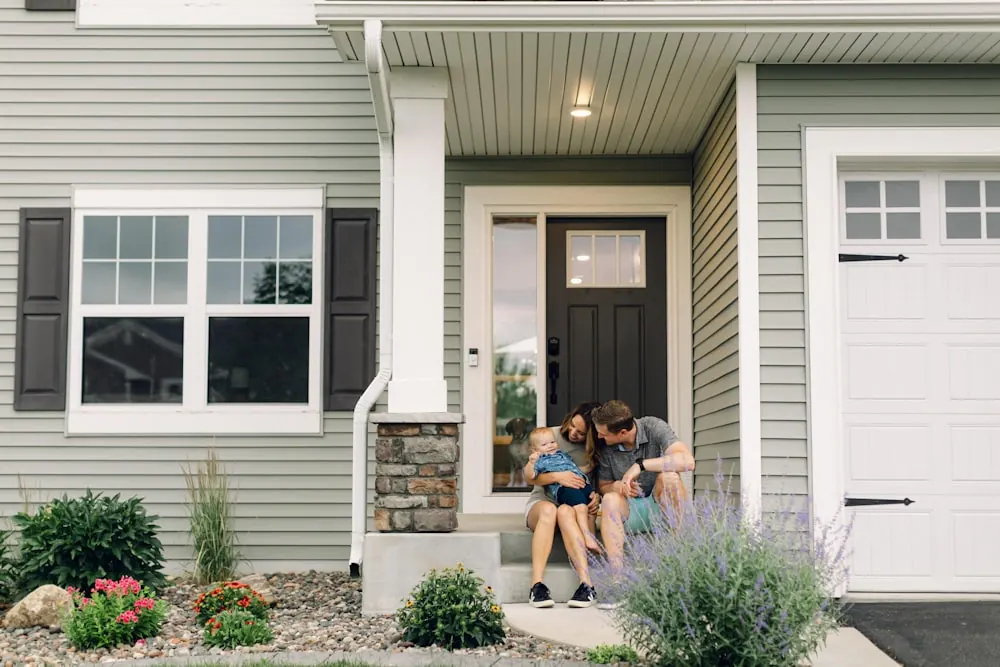 A young family sitting on the front porch of their new home