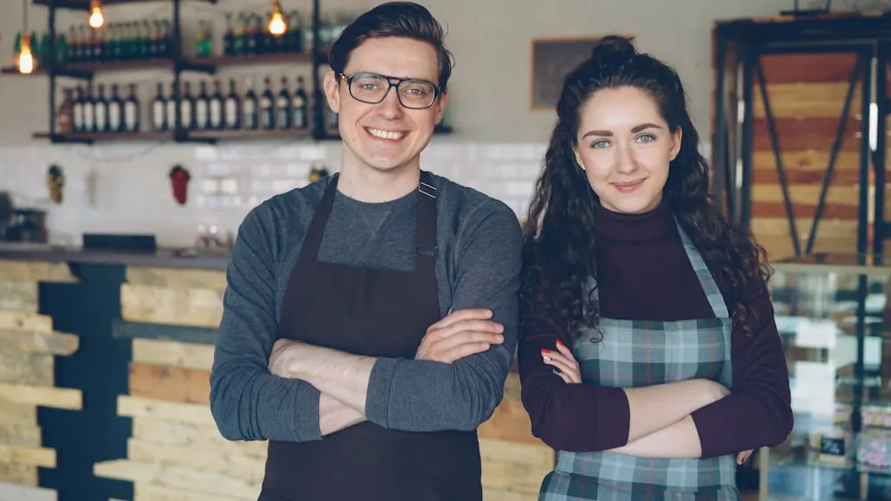 Two small business owners standing proudly in the cafe they own