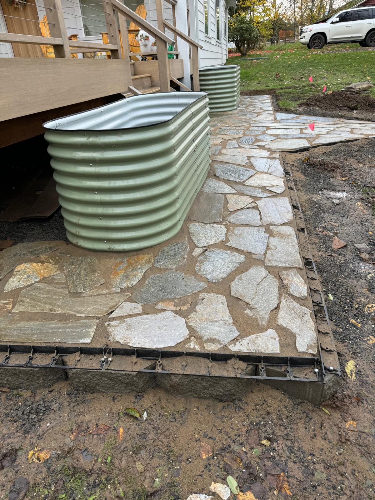 Flagstone patio beside raised planter completed by Metro Mowing Services and Maintenance LLC
