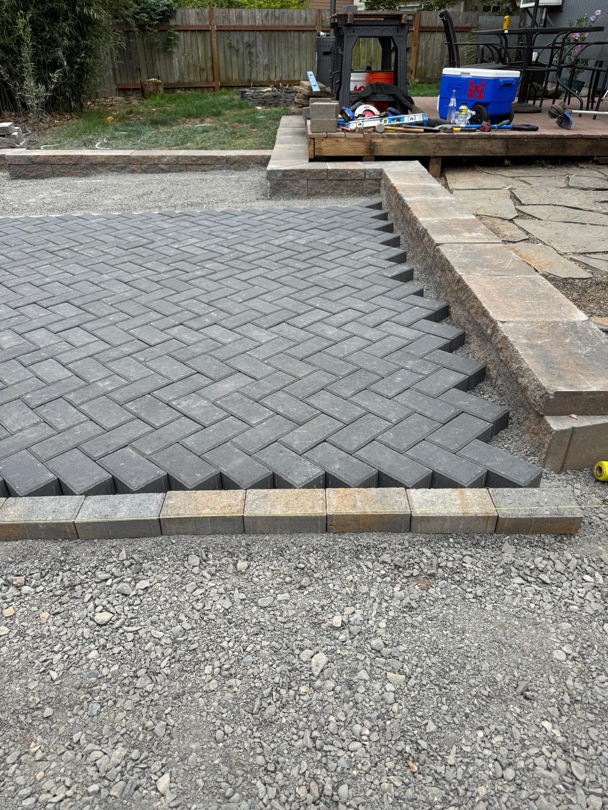 Paver patio meeting stone wall completed by Metro Mowing Services and Maintenance LLC