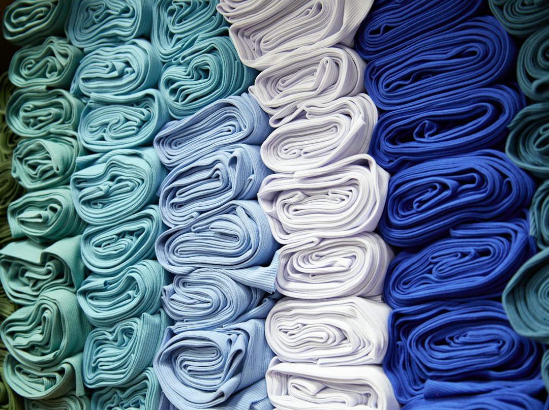 Rows of tightly folded knit fabrics in teal, pale blue, white and royal blue, stacked in graded colour columns.