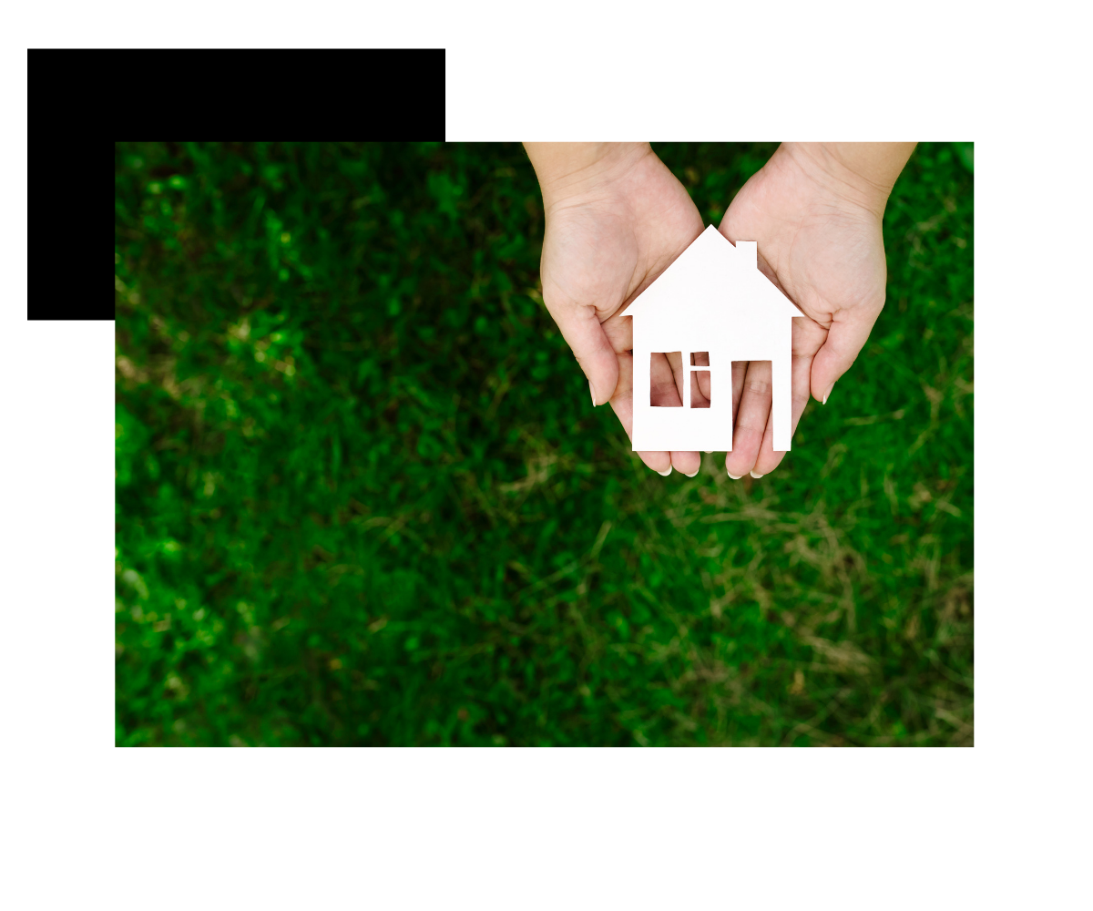 Hands holding a paper house over grass