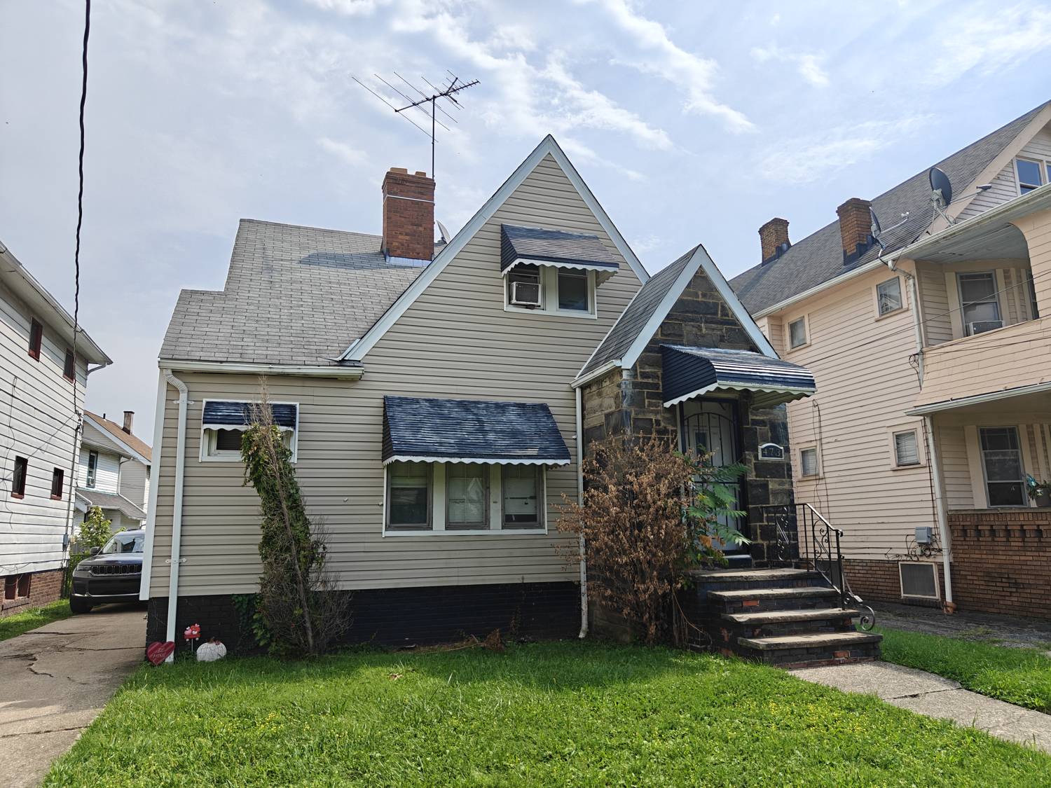 Front of 473 E 149th St, a Cape Cod with a stone faced entry and front awnings