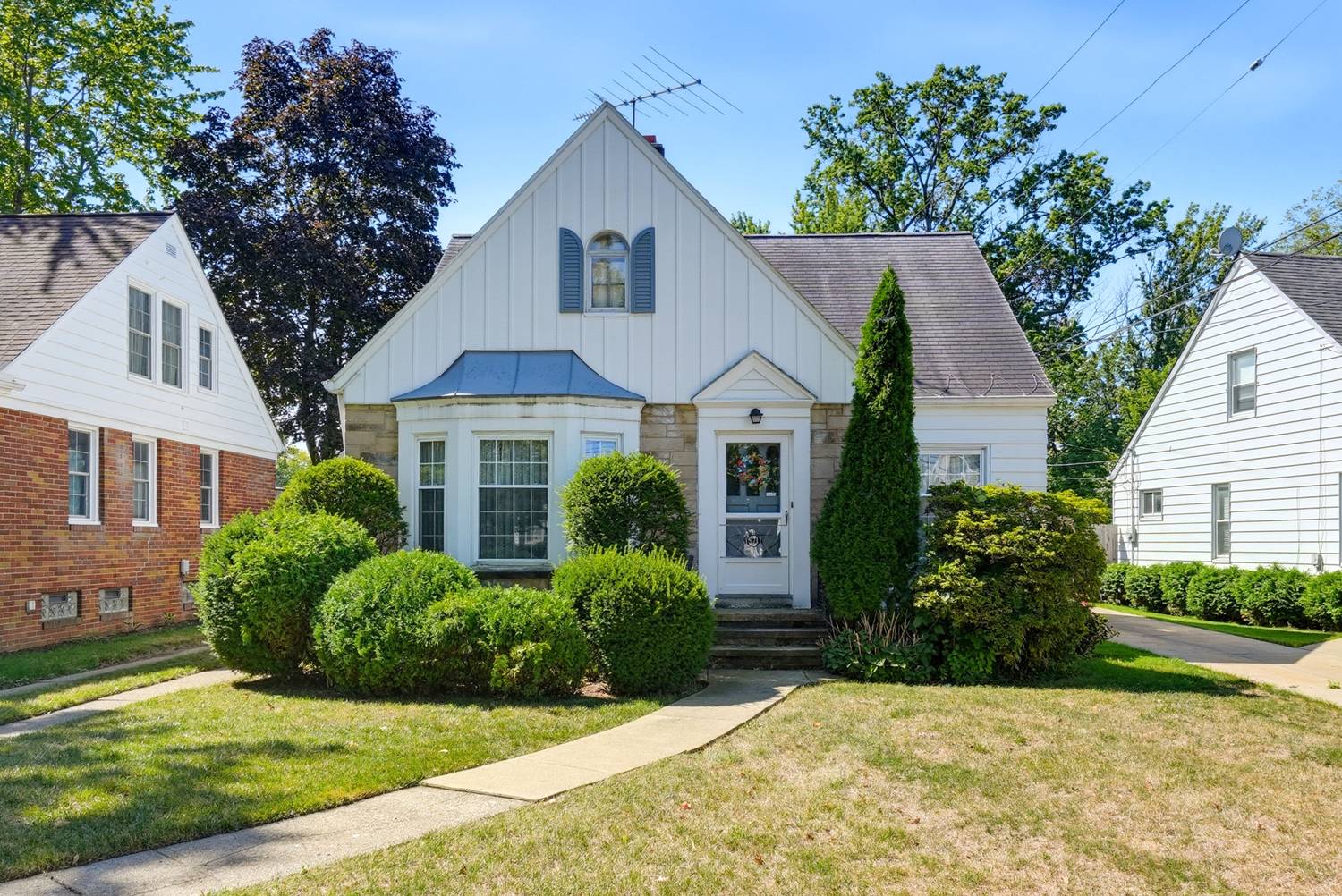 Front of 15717 Munn Rd, a 1941 Cape Cod with a stone trimmed bay window