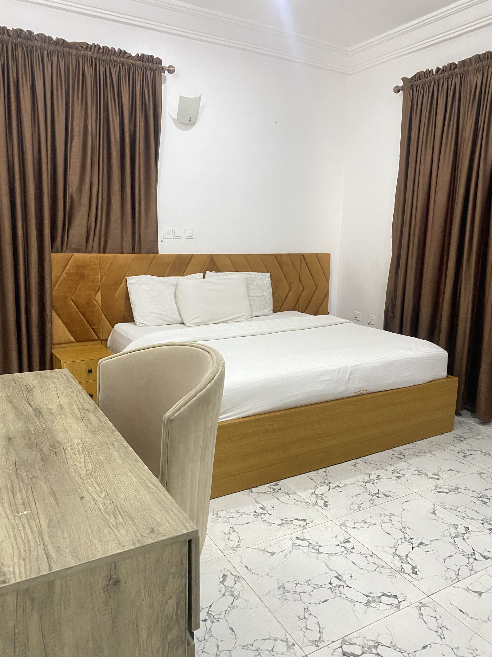 Deluxe Suite bedroom with upholstered headboard, slatted timber panelling and marble floor