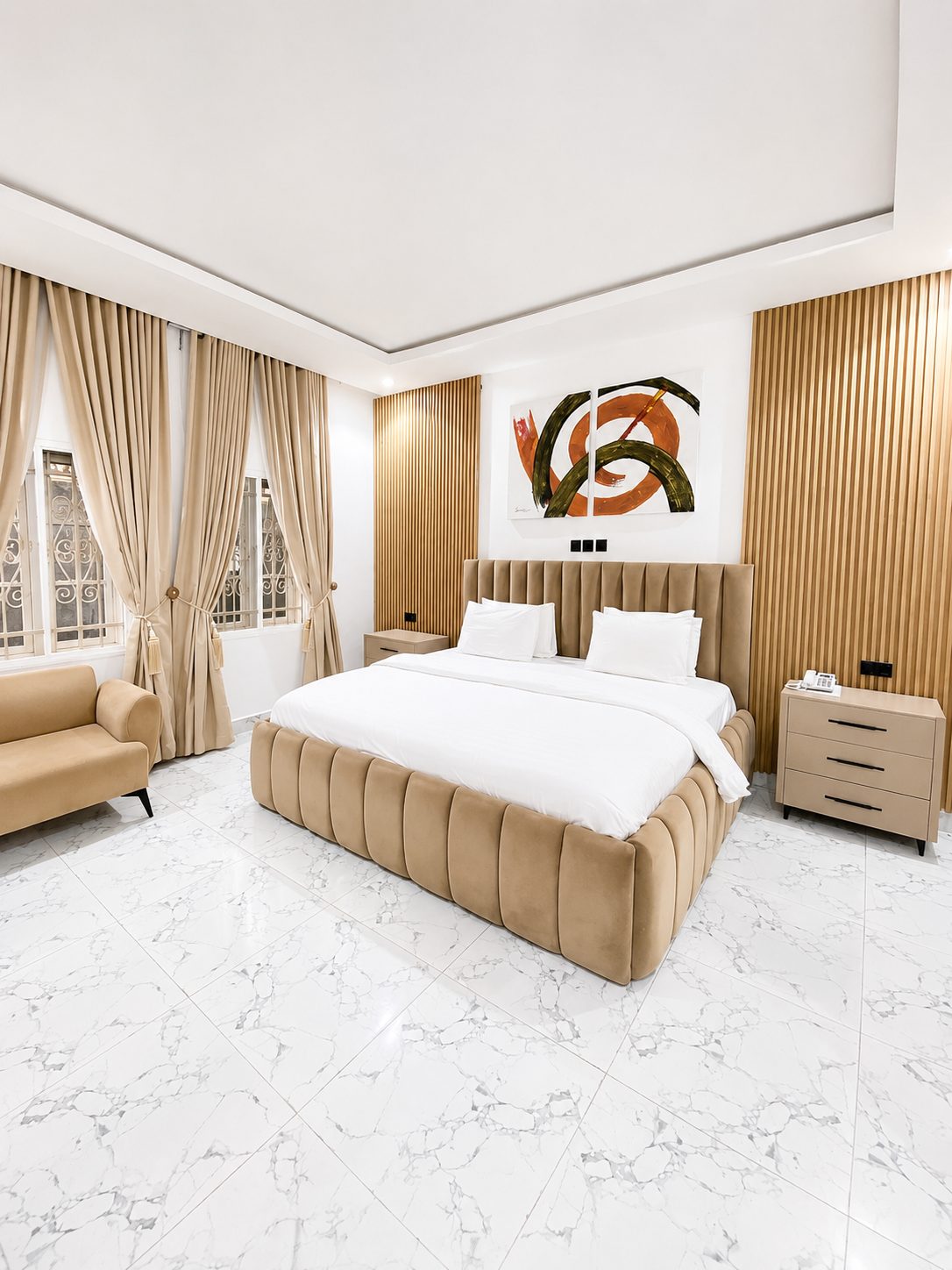 Presidential Suite bedroom with tall chevron headboard, floor-length drapery and marble flooring