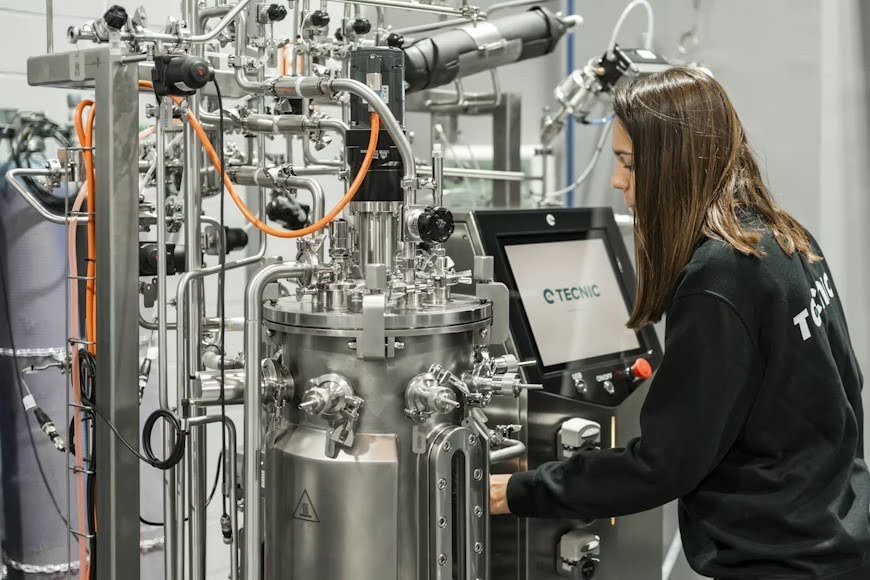 A woman building a product using a complex machine.