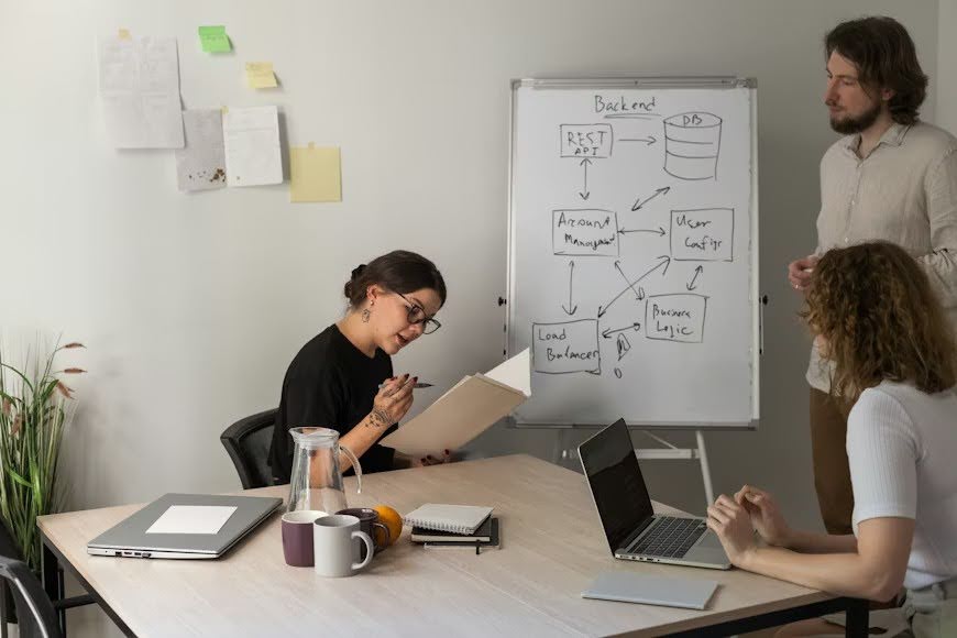 A tech team sitting around a table with their laptops, carrying out market research.