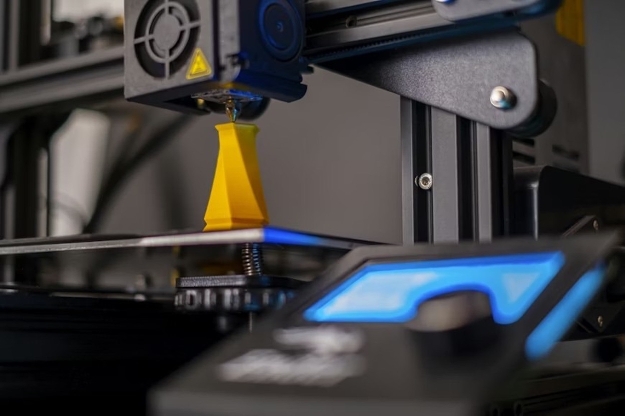 A close-up of a 3D printing machine with its blue light on A close-up of a 3D printing machine with its blue light on