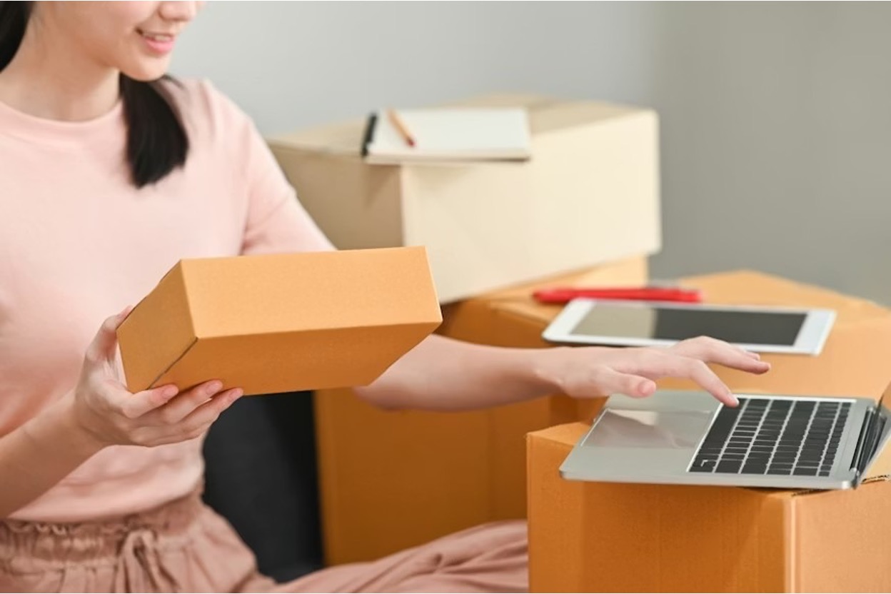 A young Asian tech professional checks product details and packs products for delivery to customers