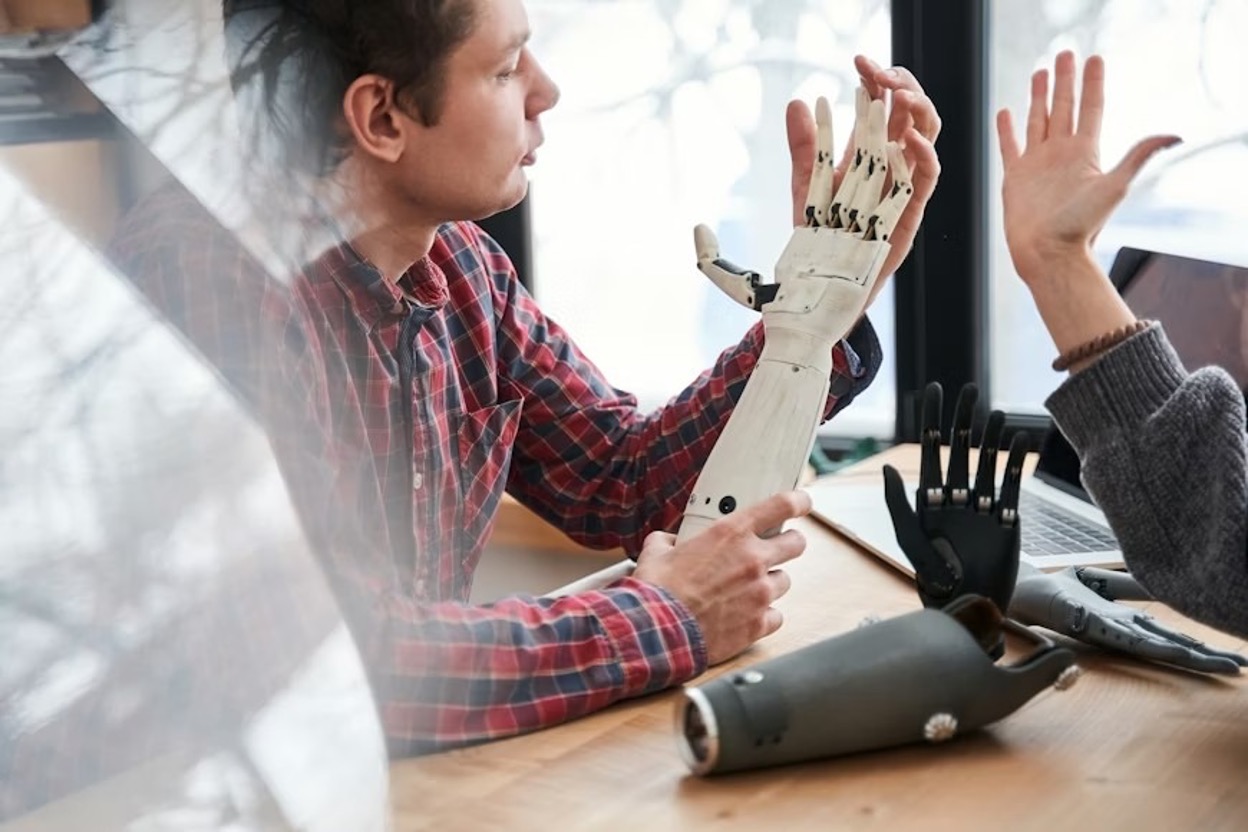 Close-up portrait of a tech team working on a prosthetic hand and comparing it with the real hand