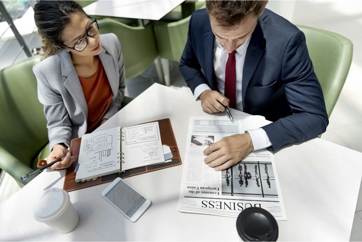 Two tech professionals are sitting at a coffee table, carrying out research before filing a patent application