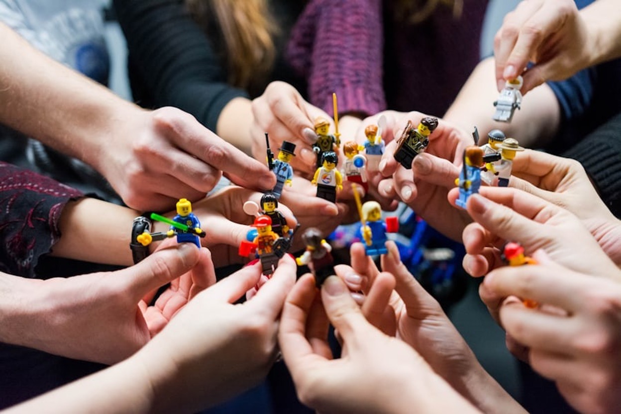 Several hands holding different toy prototypes