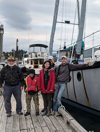 “Horizons Unbound mentors and youth standing on dock beside training sailboat
