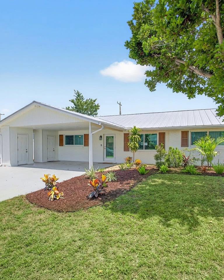 A white ranch-style home with fresh landscaping and a carport, closed by The Title Boutique