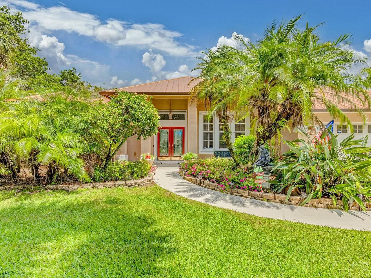 An estate home with red double doors, palm trees and a manicured lawn in Palm Beach County