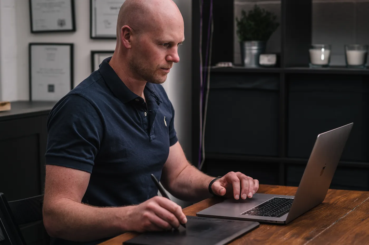 Graham at his desk, designing with a pen and tablet next to his laptop