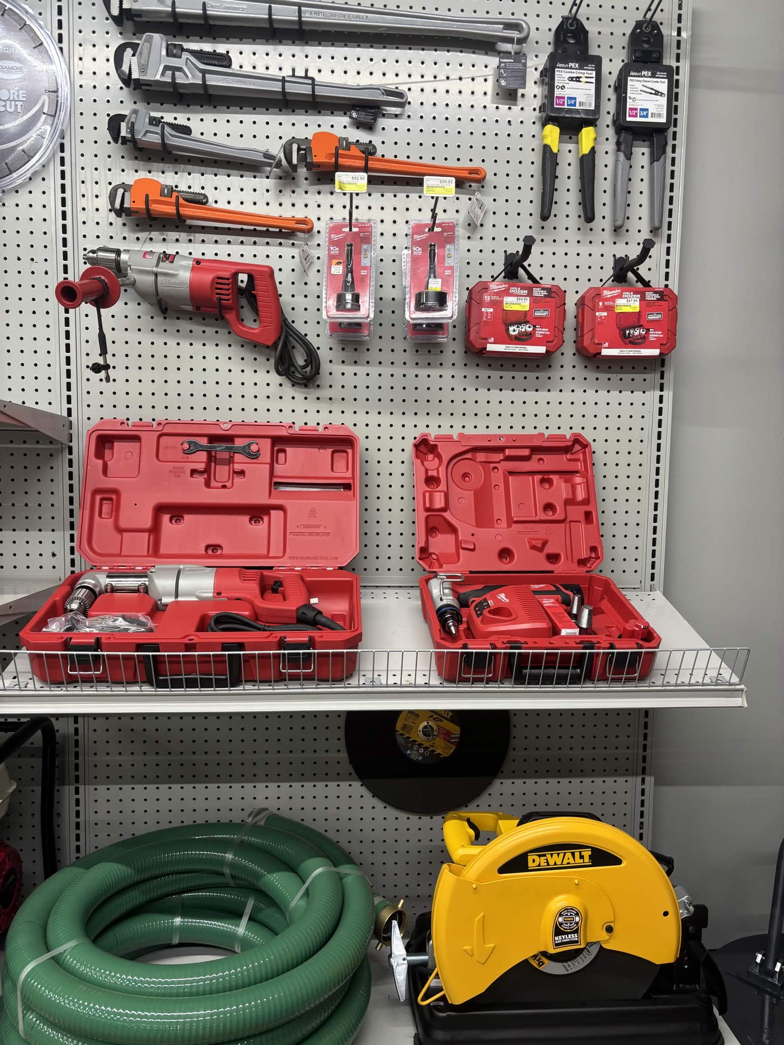 Pipe wrenches, rotary hammers, and DeWalt cut-off saw on the rental wall