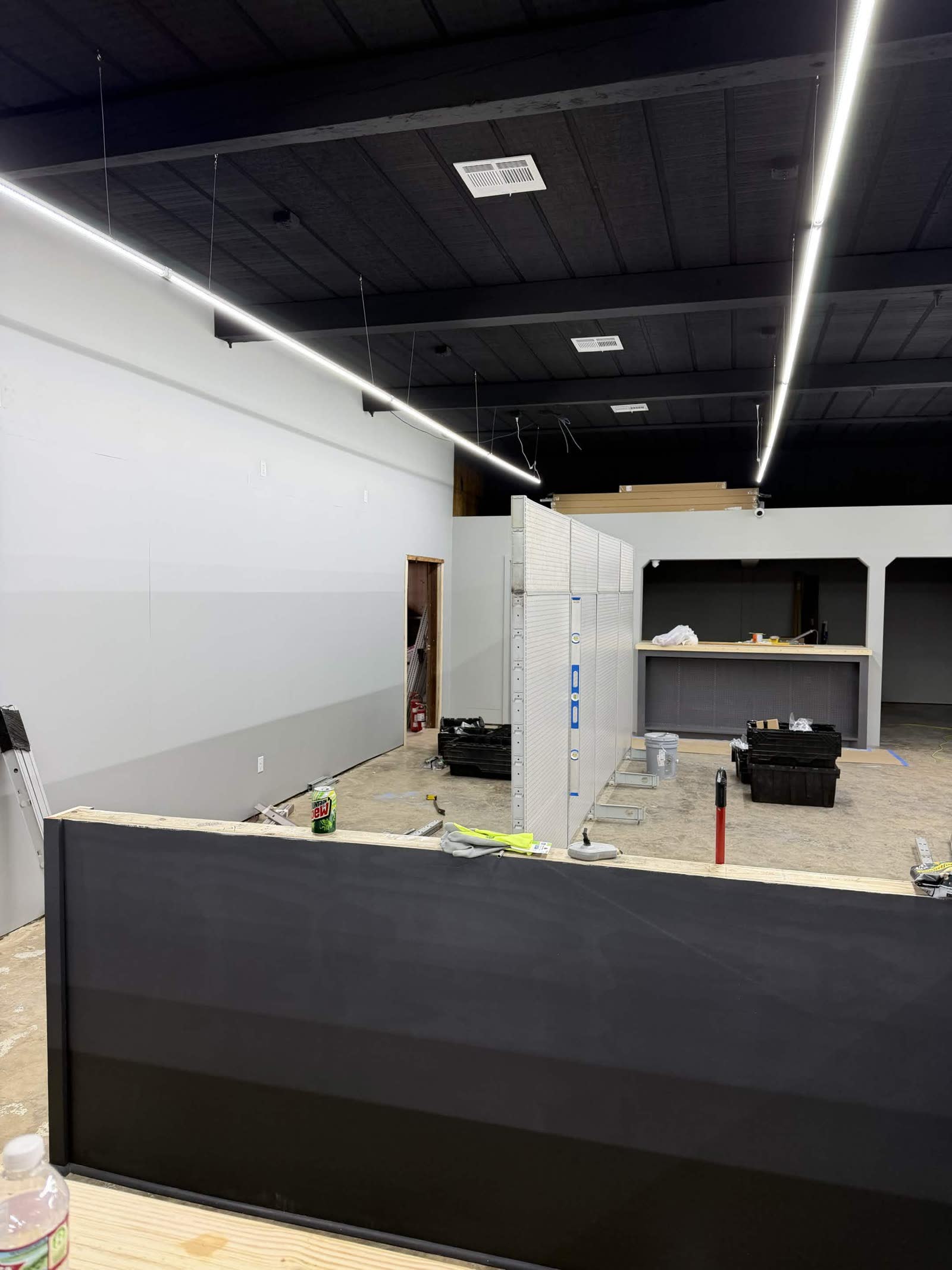 Fixtures phase — white walls painted, gray-stained concrete floor, first counter unit being assembled
