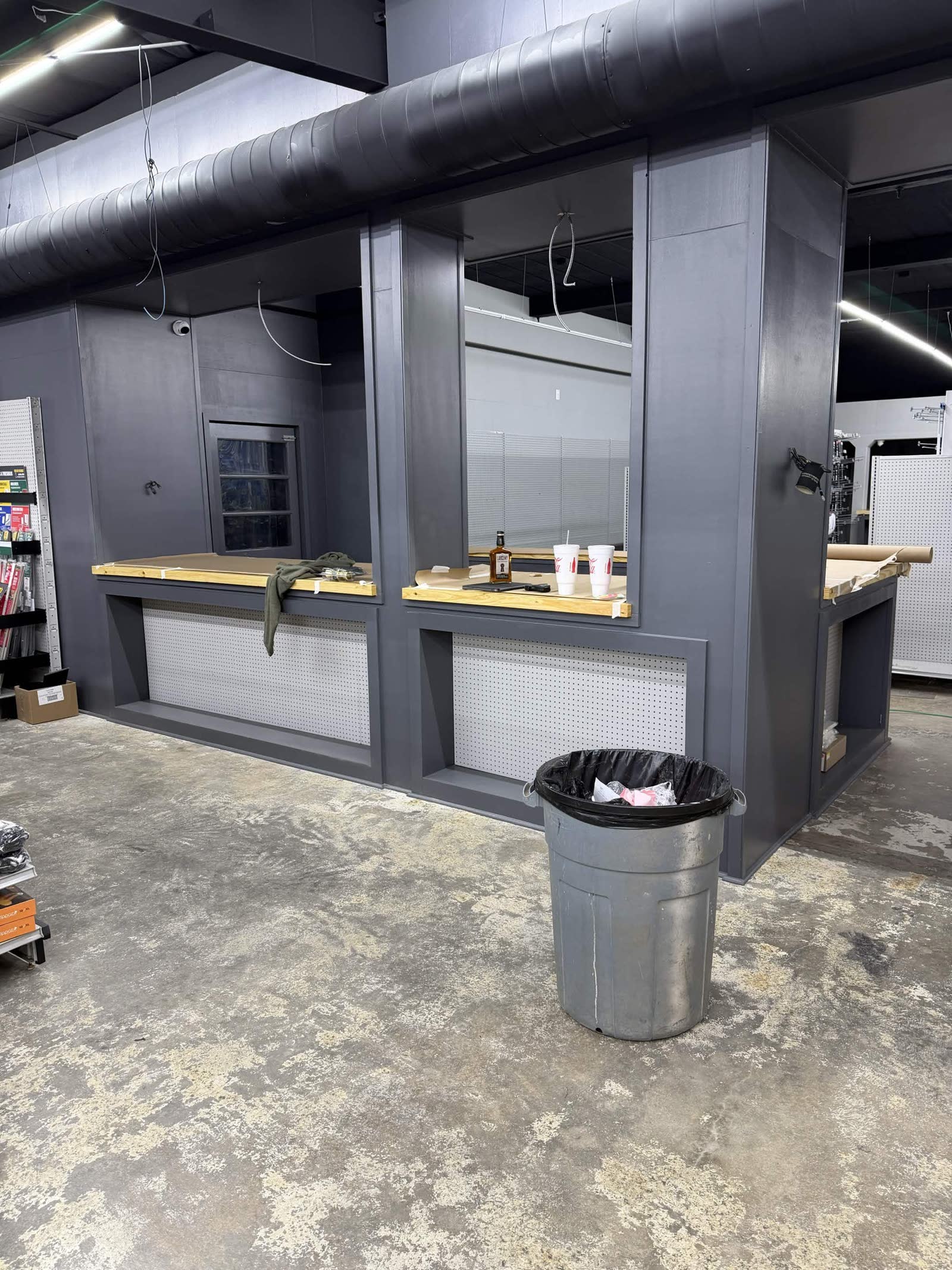 Counter under construction — gray cabinet base, butcher block tops, white pegboard panels below the counter, key-cutting machine visible on the right