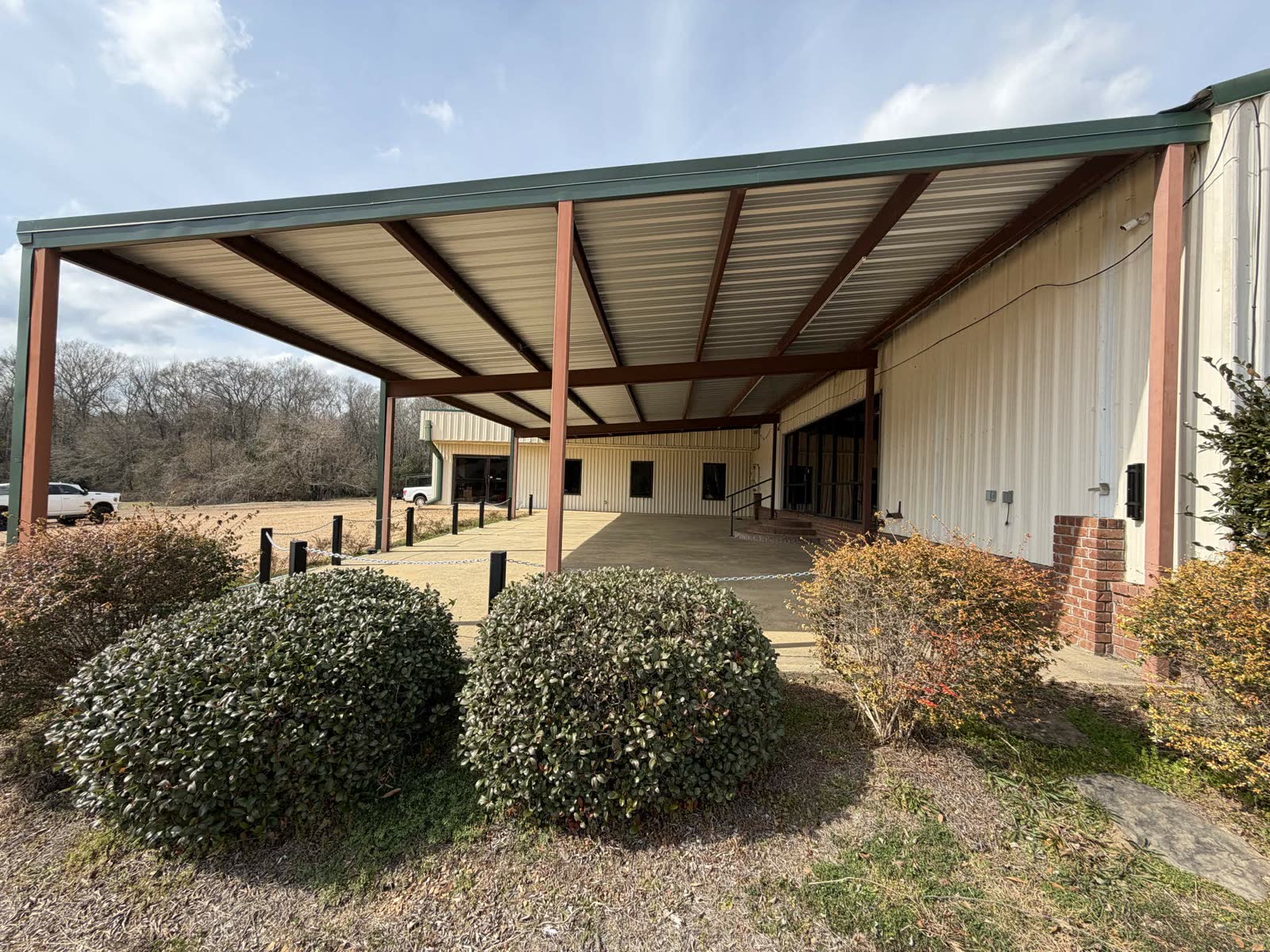 Exterior in winter — bare trees, the open covered porch, green-trimmed roof, no signage yet