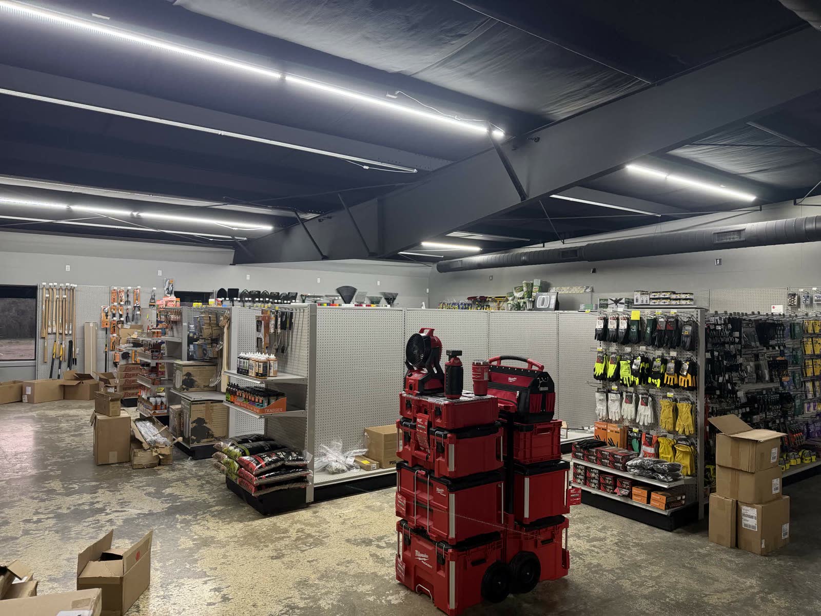 Stocking phase — Milwaukee Packout tool boxes stacked, gloves and yellow safety items on display, hand tools in the background