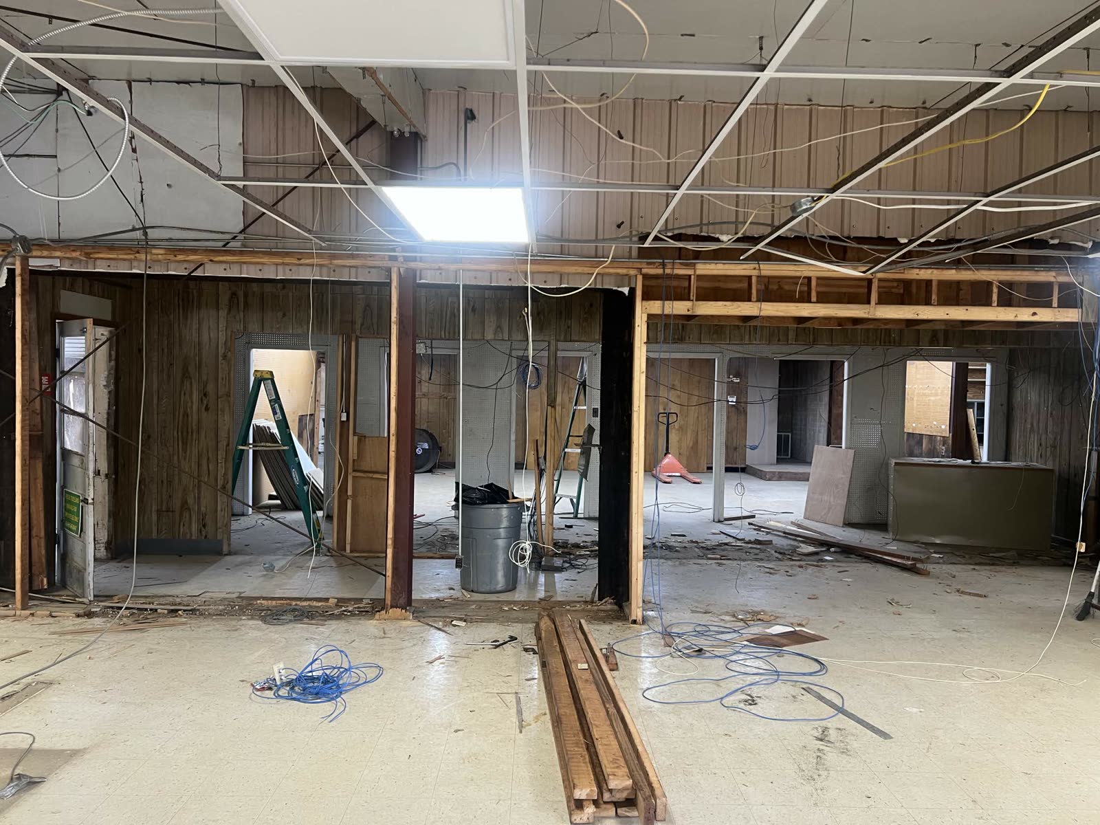 Demo phase — interior framing exposed, walls being opened up, ladder and trash cans in view