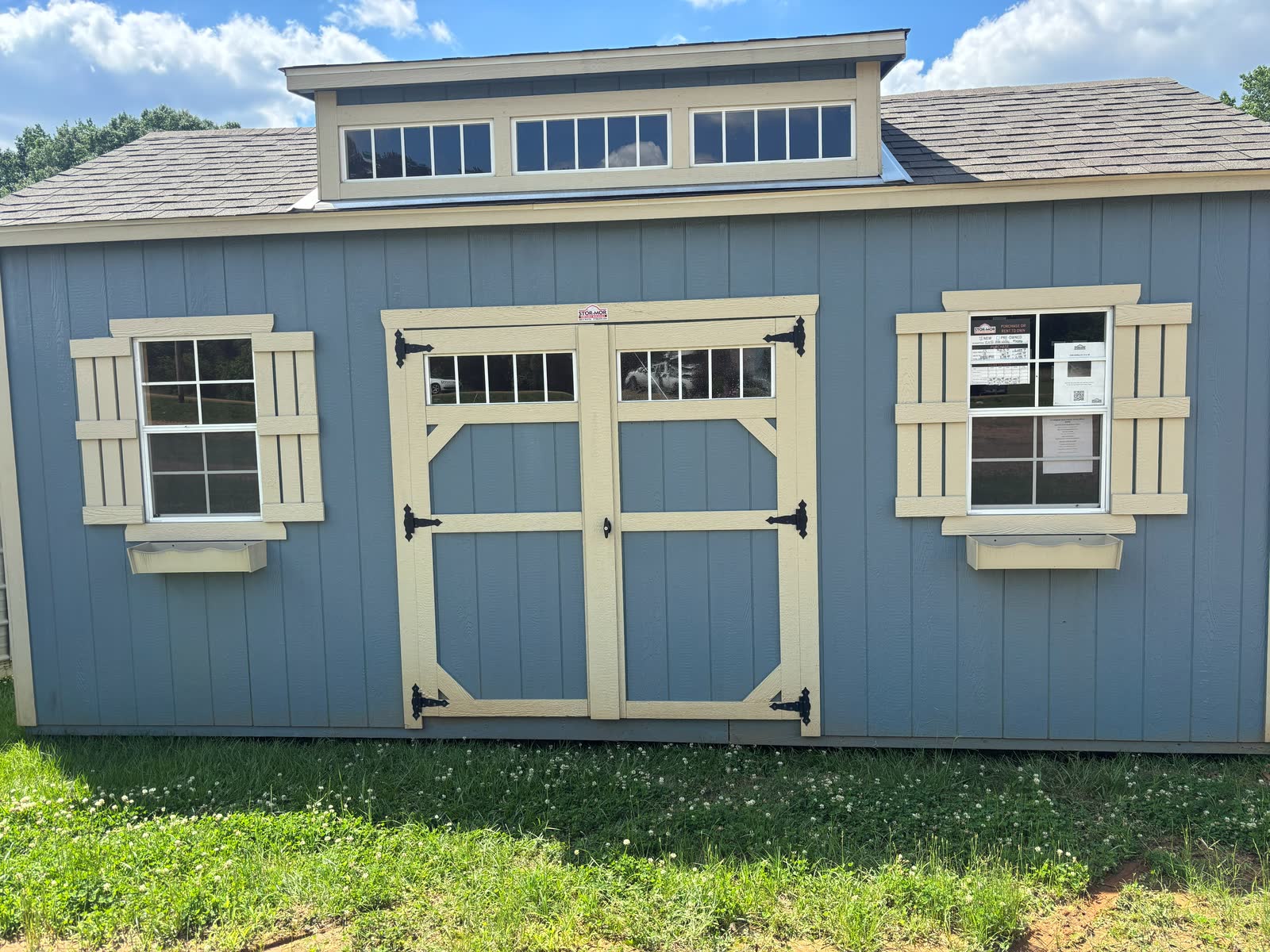 Slate-blue Stor-Mor garden shed with cupola, glass-top double doors, shuttered windows and flower boxes at Cardinal Hardware in Summit, MS