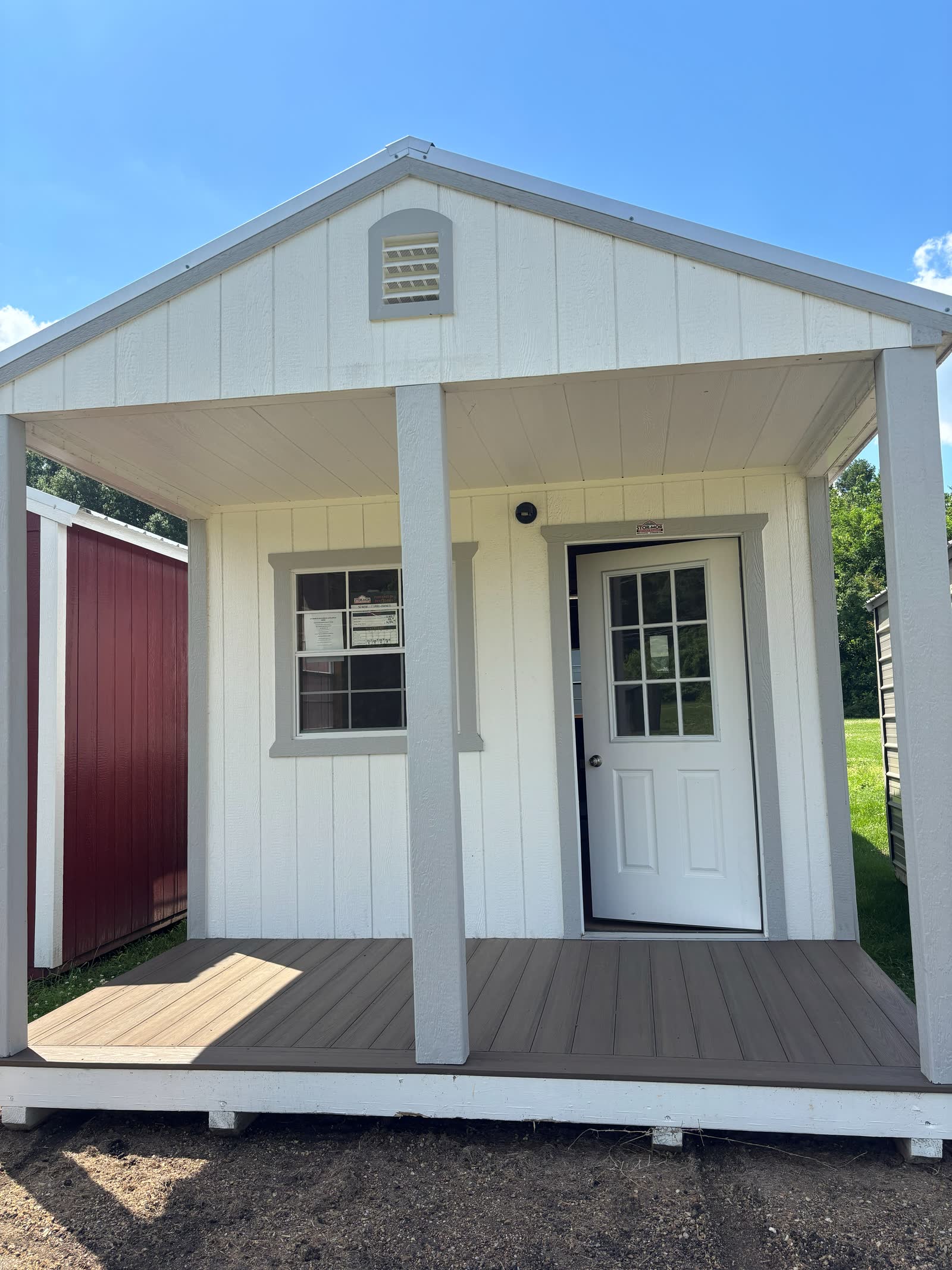 White Stor-Mor cabin with covered front porch, 9-lite door and gable vent at Cardinal Hardware in Summit, MS