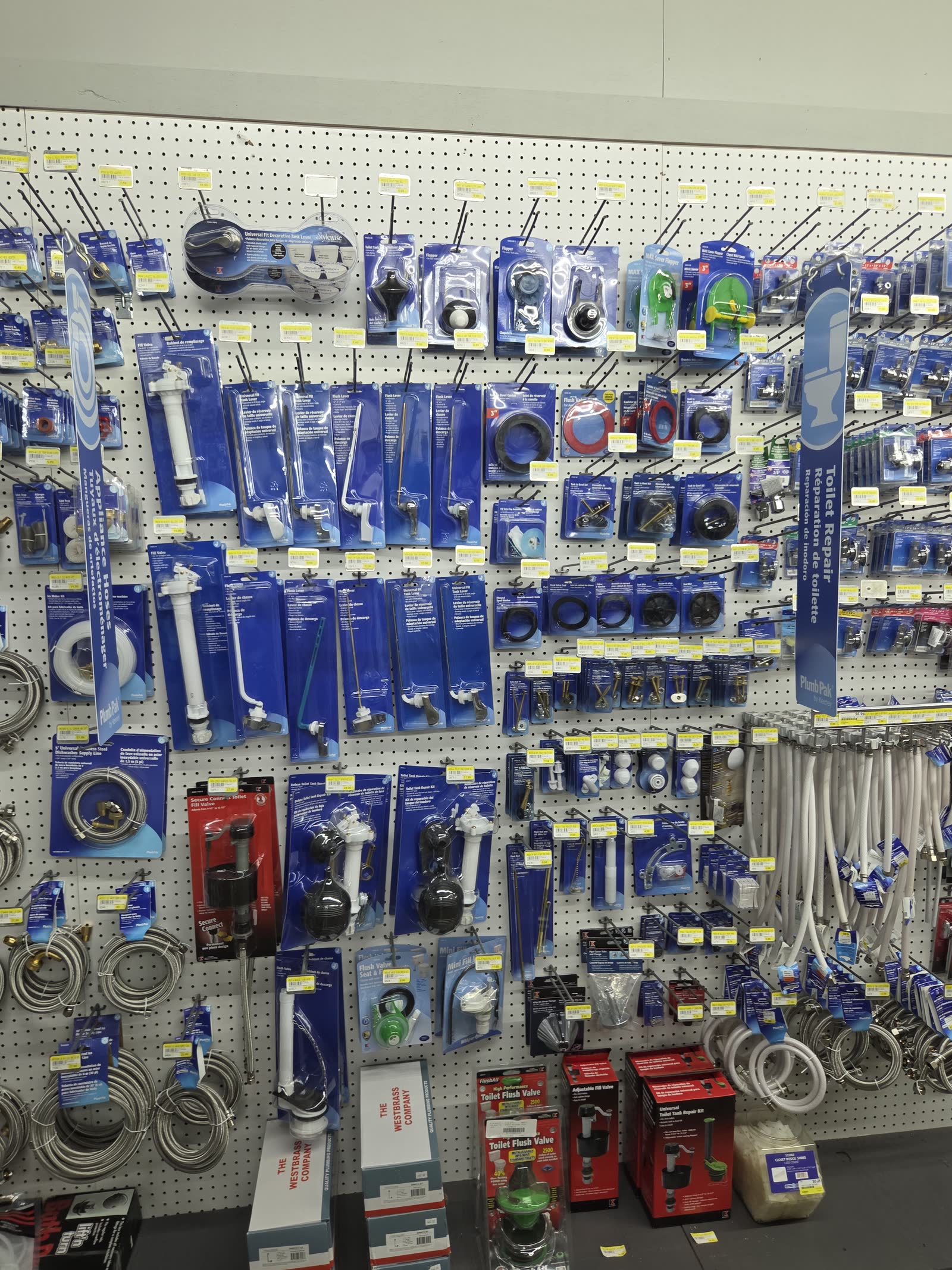 Plumbing pegboard with braided supply lines and flush valves at Cardinal Hardware