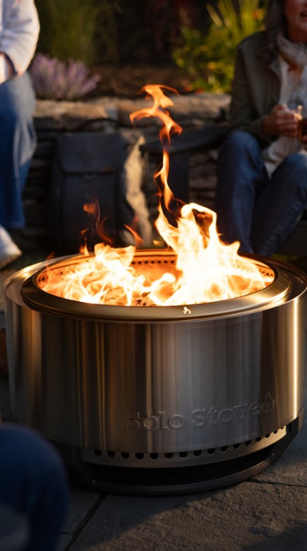 Solo Stove fire pit glowing on a patio at dusk