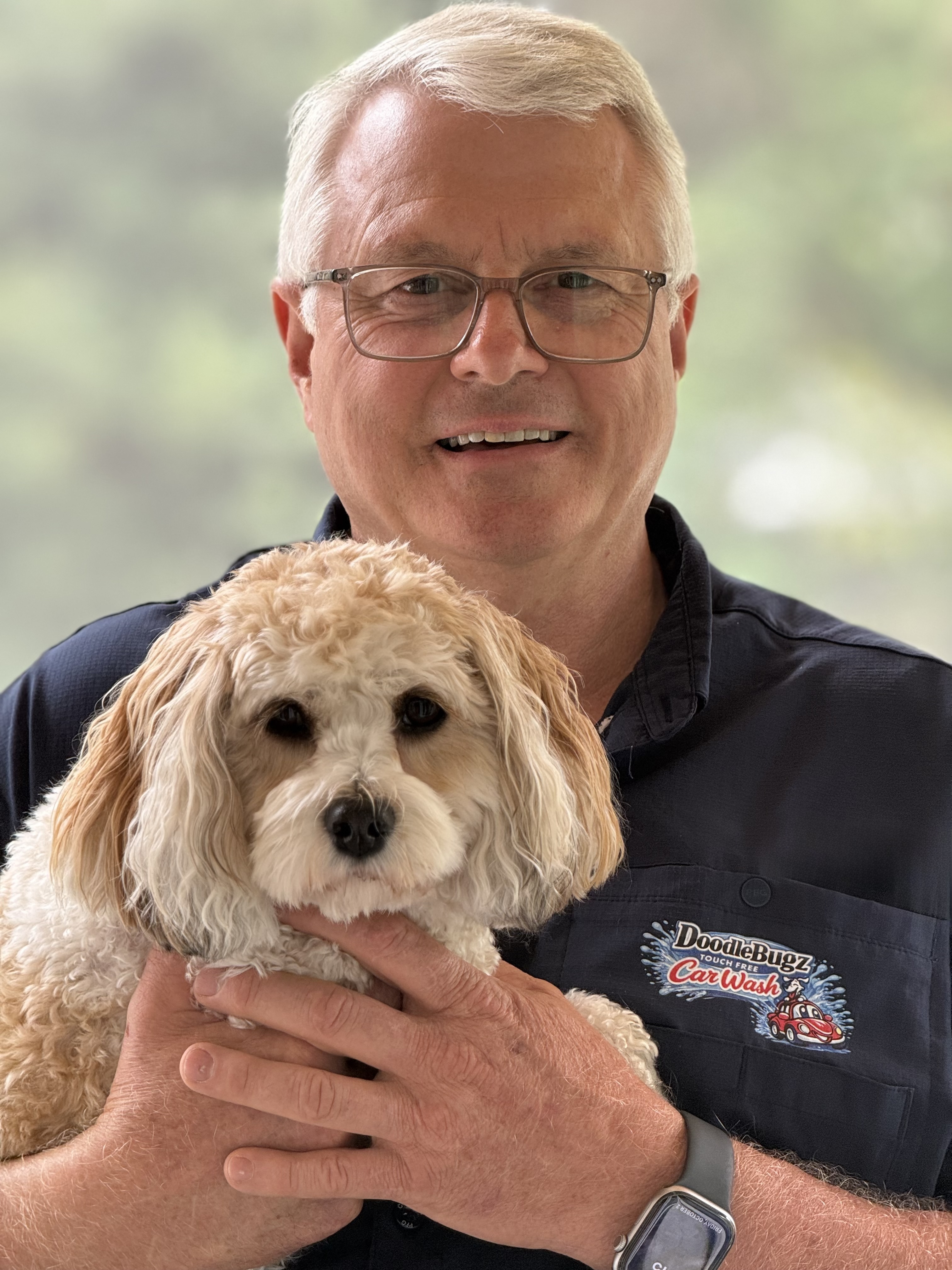 Bradley Cook holding his dog, wearing a DoodleBugz Car Wash shirt