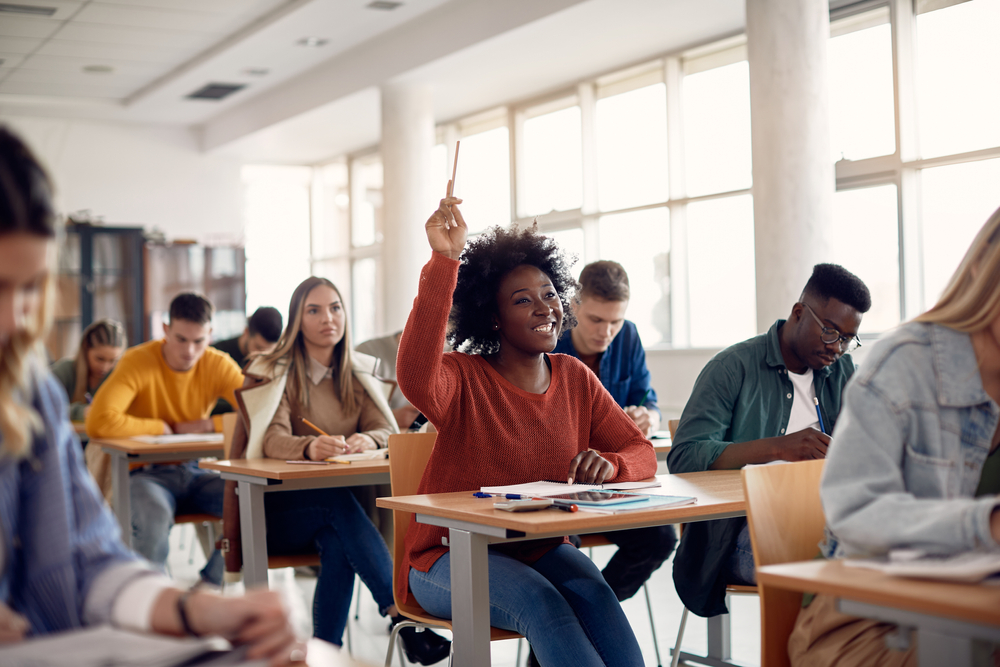 student raising her hand to ask a question