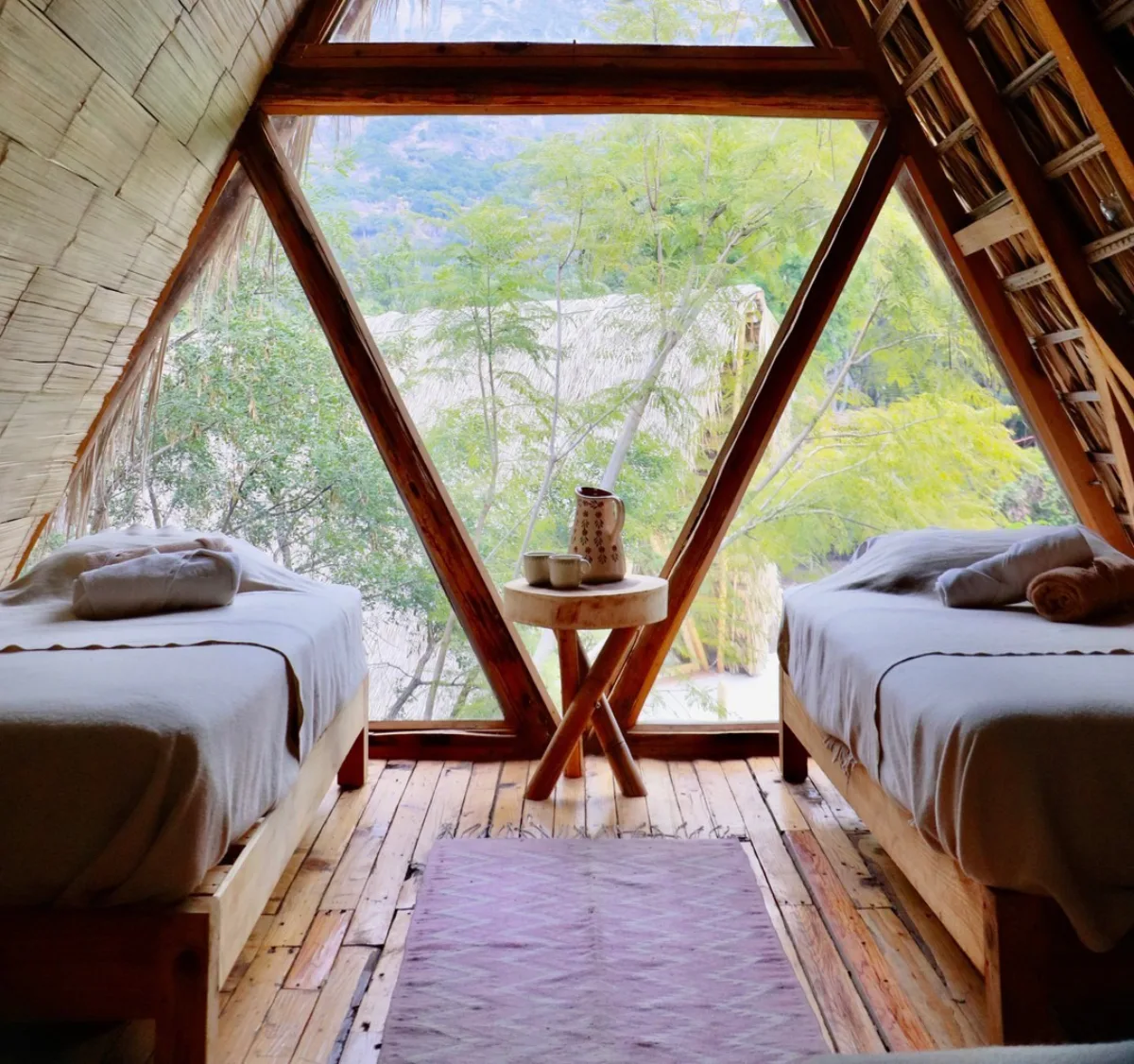 A shared A-frame room with twin beds and a triangular window over the valley, Vādma training Mexico