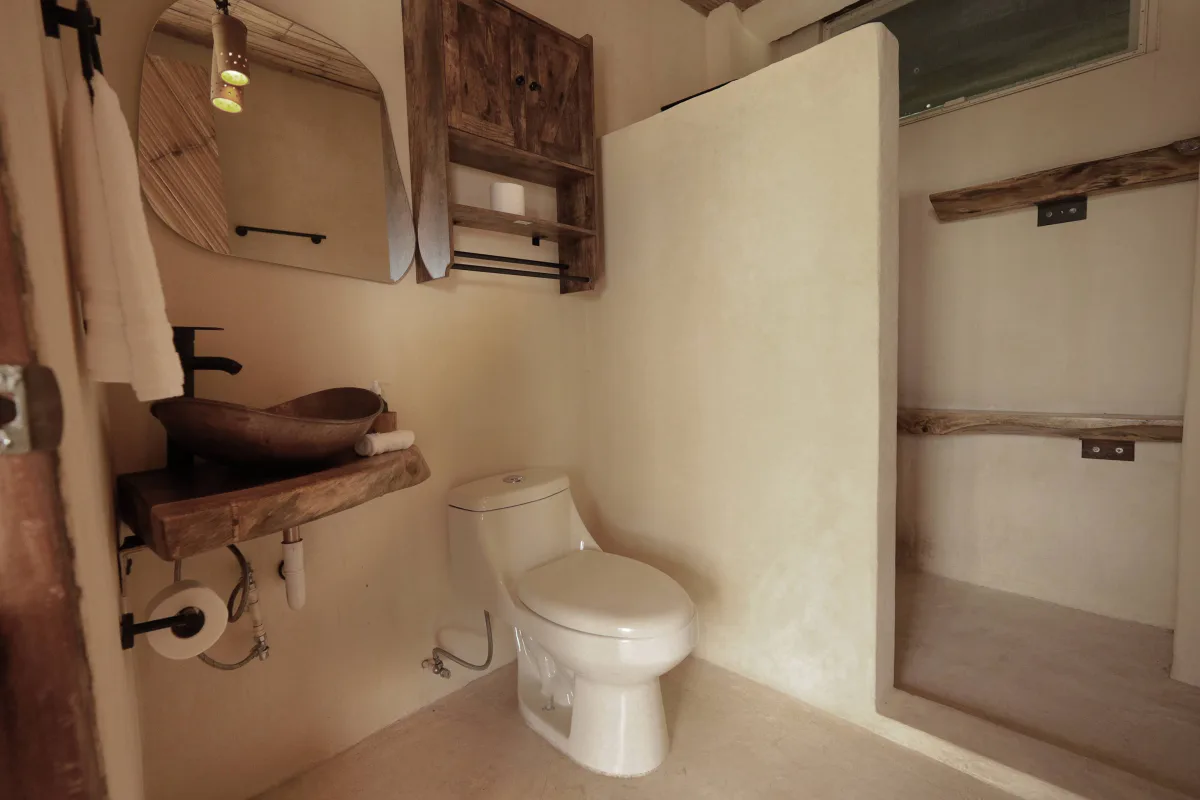 An ensuite bathroom with a carved stone basin in the Vādma Mexico training accommodation