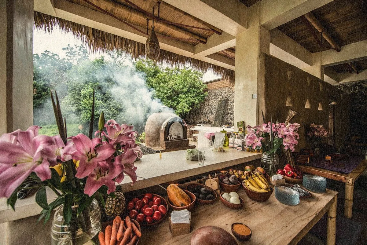 The wood-fired outdoor kitchen at the Vādma Mexico training, fresh fruit and vegetables laid out beside a clay oven