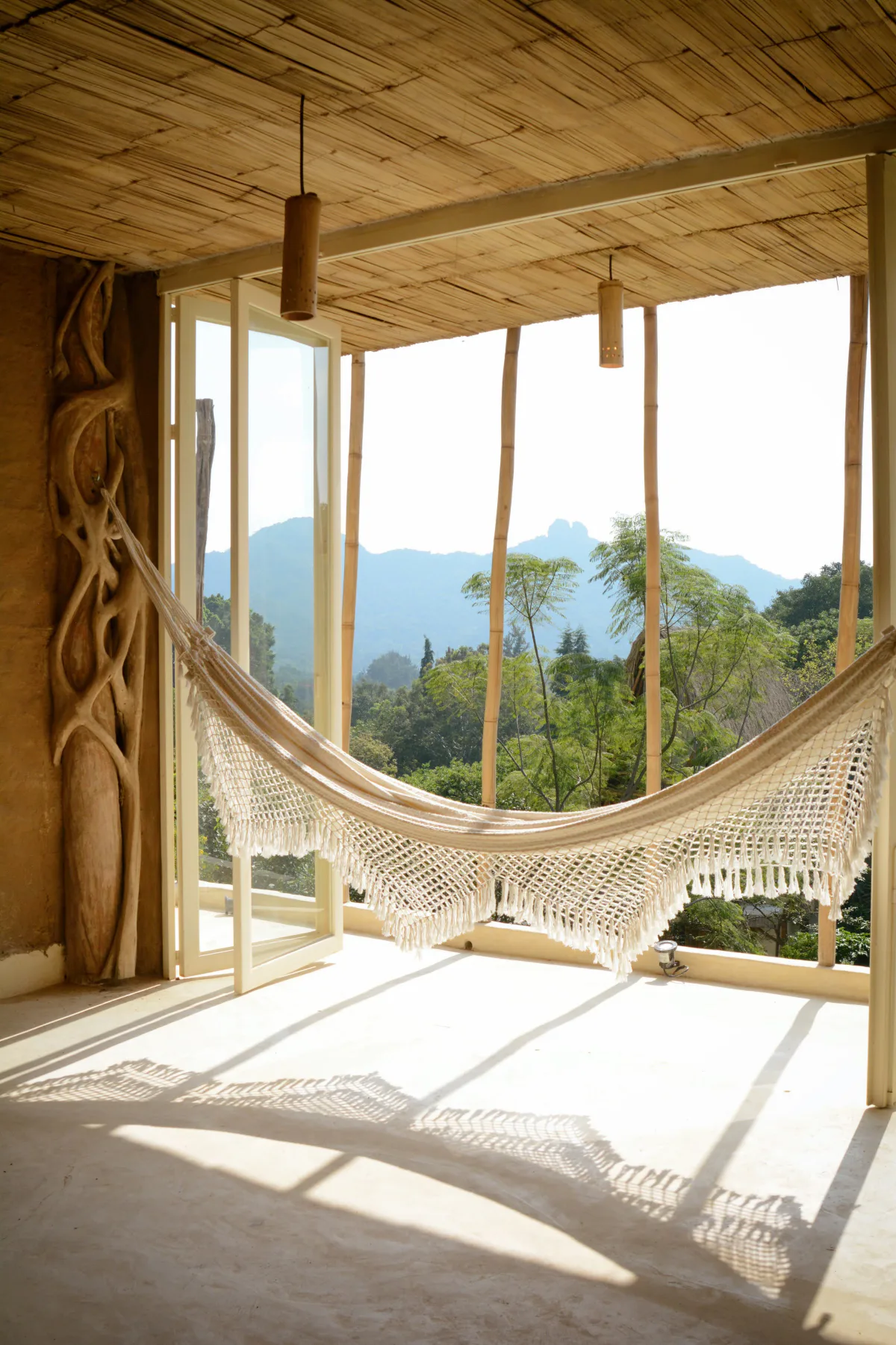 A woven hammock strung across an open room with a view to the mountains, Vādma training accommodation in Mexico