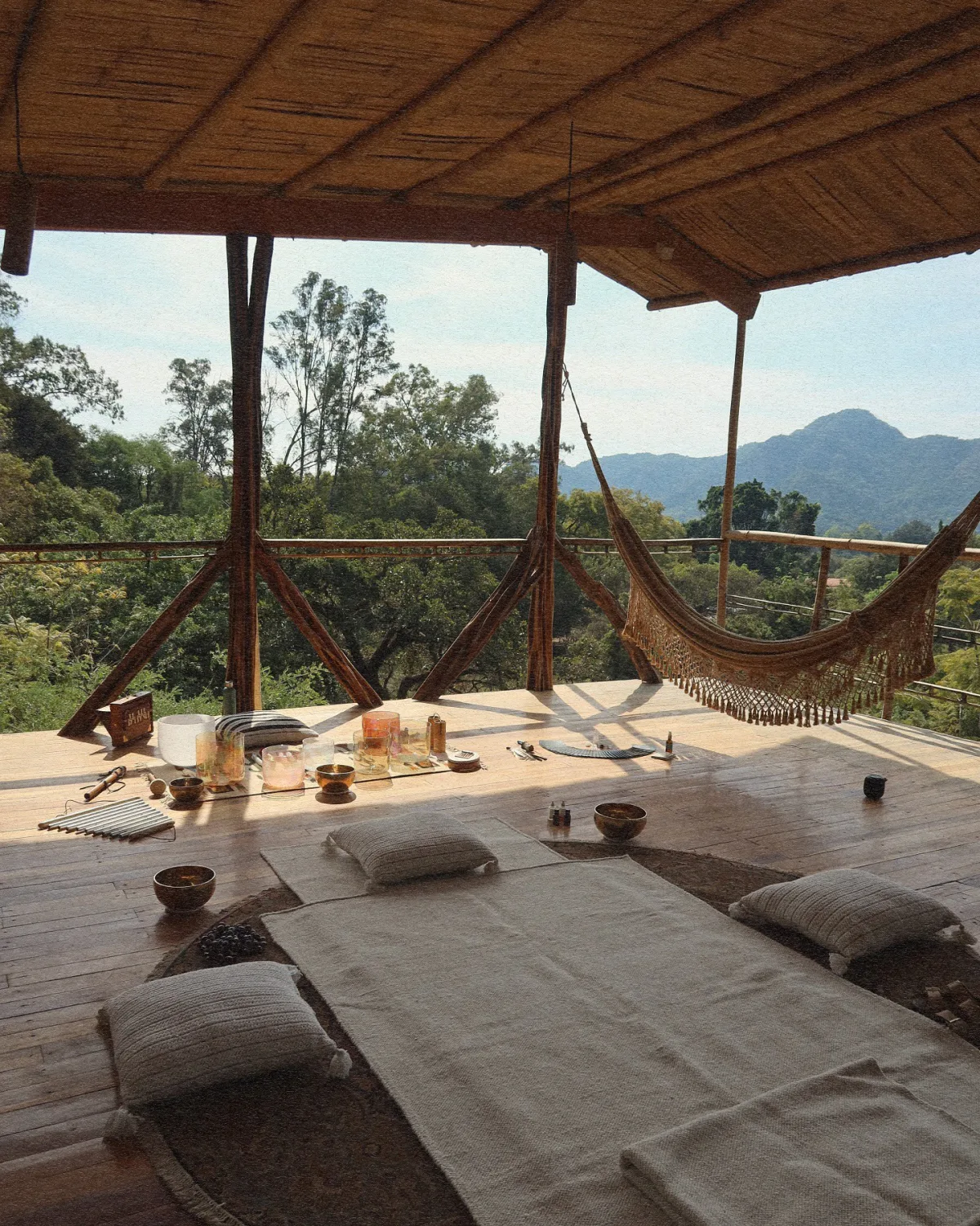 The open terrace laid out with singing bowls and mats for Vādma practice, overlooking the mountains near Mexico City