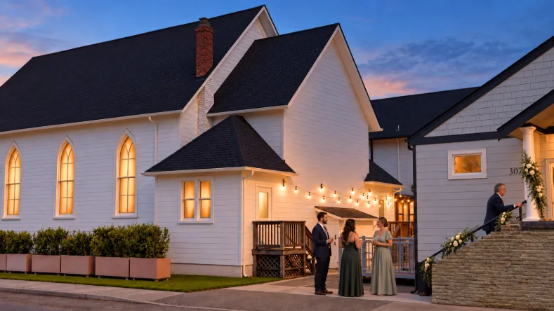 Twilight exterior of Madison Hill Chapel and reception building with warm string lights and guests mingling between the two spaces