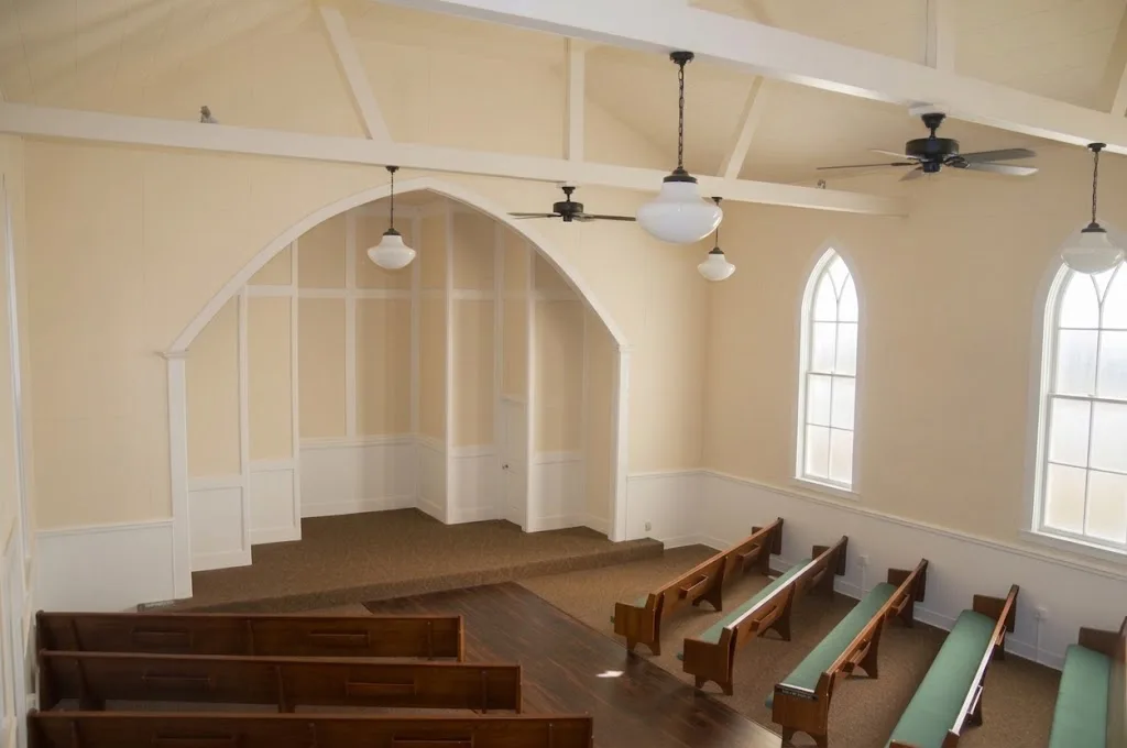Bright empty interior of Madison Hill Chapel showing pews, open ceiling, and arched architecture