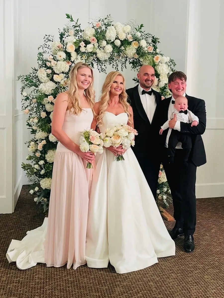 Bride and groom with family in front of the flower arch