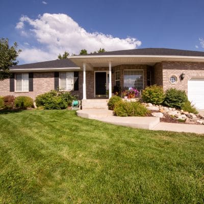 Front yard with green grass and a neatly arranged garden design.