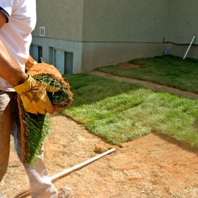 Close-up of a worker aligning sod for a new lawn installation.