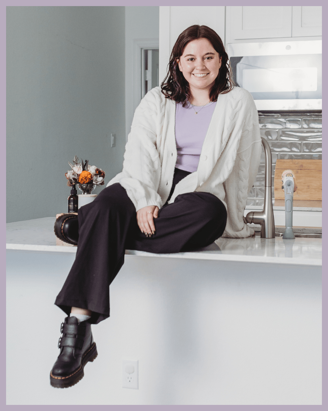 Jamie, founder of Tidy Crescent Co., sitting on a kitchen counter in a bright and organized home